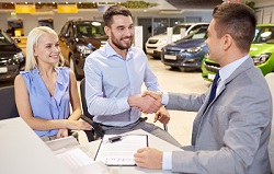Statt von der Autobank: Kredit von der Herstellerbank Junges Paar sitzt beim Verkaufsgespräch im Autohaus